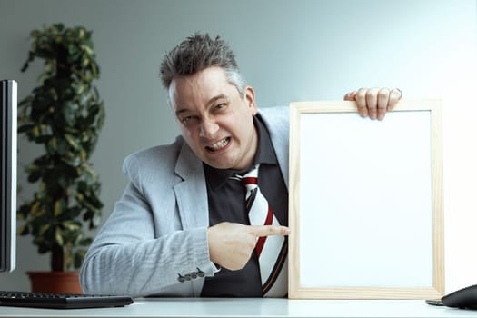 Intense middle-aged man with gray spiky hair points forcefully at a blank whiteboard. His aggressive expression contrasts with his light gray suit and colorful striped tie