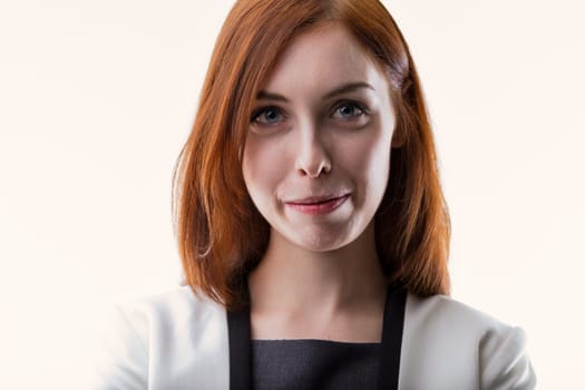 Confident woman with auburn hair, dressed in a white blazer and dark dress, looks directly into the camera. Her poised expression suggests competence and authority in her field