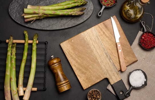 Fresh green asparagus sprouts on a black wooden background. View from above