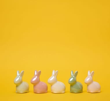Ceramic decorative bunnies on a yellow background, festive Easter background