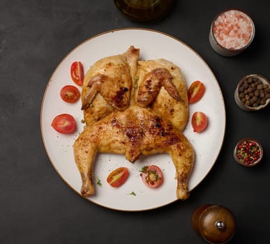 Whole fried chicken with spices in a white round plate on the table, top view