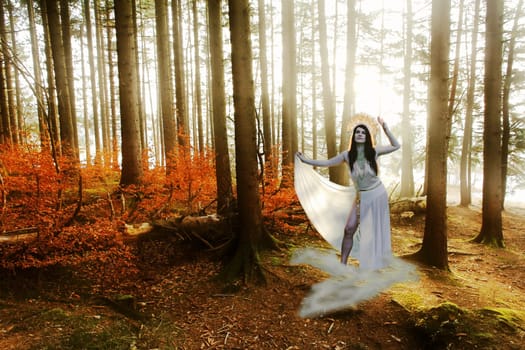 A woman as a goddess stands on a cloud in the forest, backlit by the sun