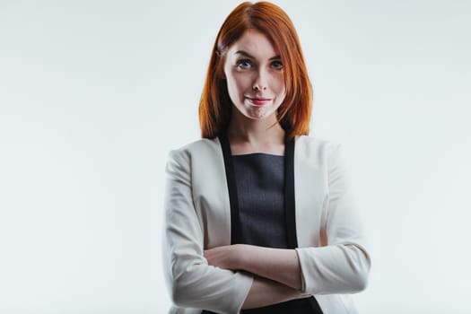 Professional-looking female with bright red hair and a playful smirk, dressed in a stylish gray blazer, exudes confidence