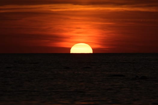Sunset on the horizon of the Baltic Sea. Romantic evening atmosphere by the sea. Orange sun sinks into the water. Landscape photo