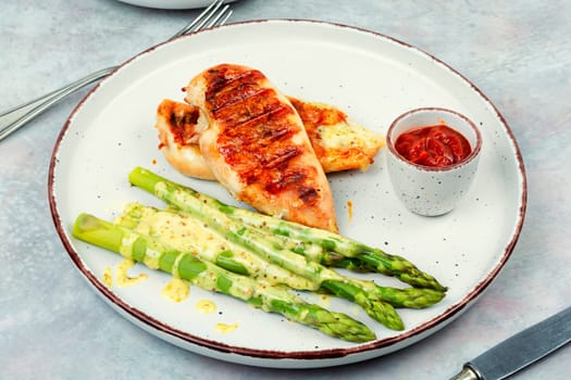 Roasted or grilled chicken breasts with green asparagus. Healthy eating concept.