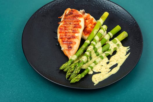 Roasted or grilled chicken breasts with green asparagus. Healthy eating concept.