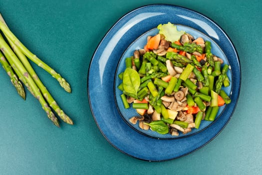 Vegetable detox salad of green asparagus and fried mushrooms on a plate. Healthy food. Space for text.