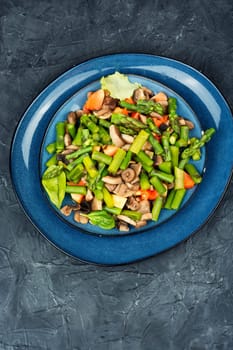 Vegetable detox salad of green asparagus and fried mushrooms on a plate. Healthy food. Space for text.