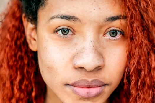 Black teenage girl with red dyed hair and afro hairstyle.