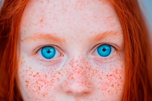 Close up portrait of red-haired young school age girl with bright blue eyes, red hair and freckles.