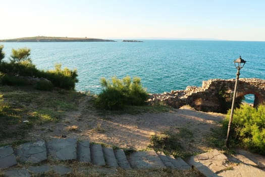 The ruins of a gate of the ancient city wall in the old town of Sozopol, Sosopol, the St. Saint Ivan Island can be seen in the background, Bulgaria 2022