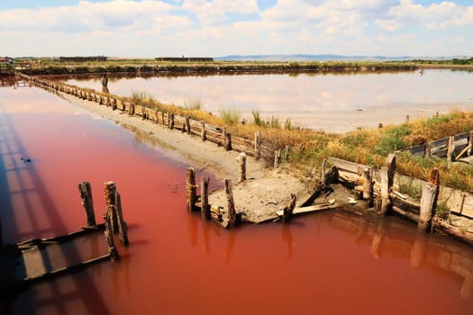 Board walks running through the different pools of the Burgas Salt Pans, filled with pink water, the clouds in the sky are reflecting in the water, Lake Atanasovsko, Atanasovo, Burgas, Bourgas, Bulgaria 2022