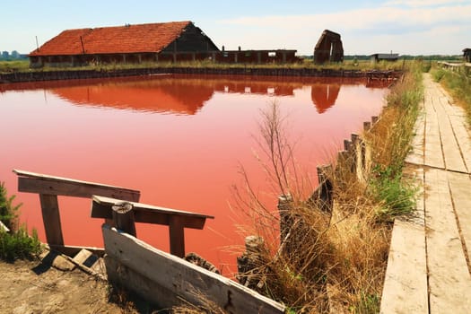 Wooden board walk and stairs leading into the main bathing, swimming pool with its intense pink color at the Burgas Salt Pans, Lake Atanasovsko, Atanasovo, Burgas, Bourgas, Bulgaria 2022