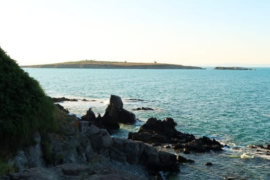 View from a beach in the old town of Sozopol, Sosopol onto St. Saint Ivan Island, black rocks in the foreground, Bulgaria 2022