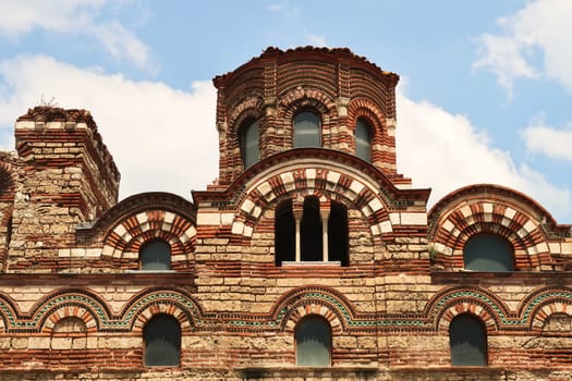 The upper facade of the Church of Christ Pantocrator in the old town of Nessebar, Nesebar, elaborate patterns out of bricks and colorful tiles, windows and the roof, Bulgaria 2022