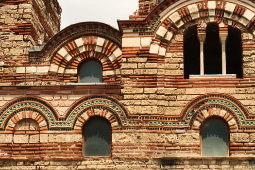 The beautiful facade of the Church of Christ Pantocrator in the old town of Nessebar, Nesebar, elaborate patterns out of bricks and colorful tiles around the windows, Bulgaria 2022