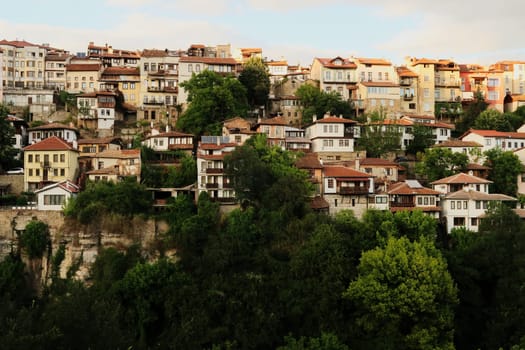 Beautiful view onto one of the neighborhoods of the old town of Veliko Tarnovo, rising above a dense forest, Veliko Tarnovo, Bulgaria 2022