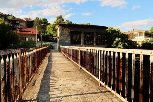 Walking over an abandoned dam on the Yantra River, rusted, rusty railings, handrails, rails on both sides of the concrete bridge, Veliko Tarnovo, Bulgaria 2022