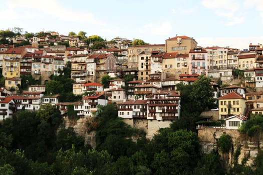 Picturesque view onto one of the neighborhoods of the old town of Veliko Tarnovo, rising above a dense forest, Veliko Tarnovo, Bulgaria 2022