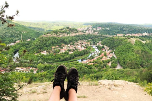 Sitting on the love swing on Garga Bair, black shoes in front of a scenic view over the city of Veliko Tarnovo and the lush dense forest that surrounds it, Veliko Tarnovo, Bulgaria 2022