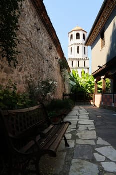 Inside the courtyard of the St., Saint Konstantin & Elena Church, the bell tower and a garden can be seen in the background, a bench in the foreground, Plovdiv, Plowdiw, Bulgaria 2022