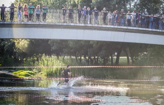 Merida, Spain - May 18th, 2024: FarinatoRace Merida 2024, Participant crossing the Albarregas river