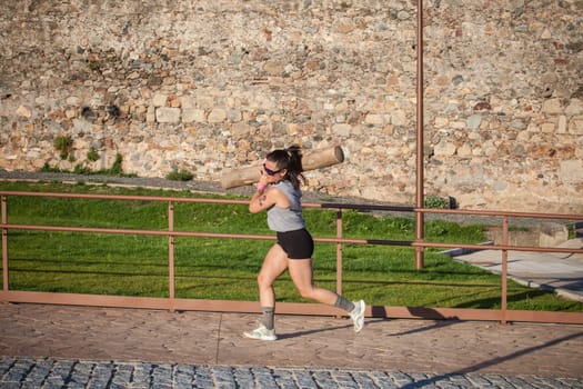 Merida, Spain - May 18th, 2024: FarinatoRace Merida 2024. Woman carrying a heavy log on his shoulder