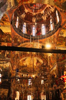 The elaborate decoration inside the Church St., Saint Archangels Michael and Gabriel at the Bachkovo Monastery, colorful frescos, ceiling, wall paintings and golden chandeliers, close to Plovdiv, Bulgaria 2022