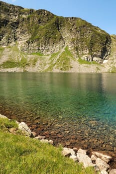 The mountains are reflecting in the blue, green, turquoise water of the Kidney, Babreka Lake, one of the Seven Rila Lakes, situated on a plateau in the Rila National Park, close to Sofia, Bulgaria 2022