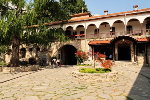 View onto the entrance gate to the Bachkovo Monastery from the courtyard inside, visitors and a souvenir shop are visible, close to Plovdiv, Bulgaria, 16th of July 2022