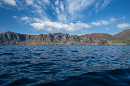 Norwegian fjord landscape. View of mountains with rugged vegetation. Crystal clear water in the foreground. Landscape from Scandinavia