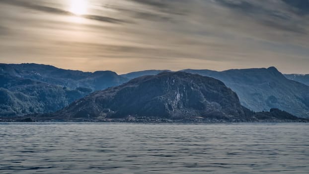Norwegian fjord landscape. View of mountains with rugged vegetation. Crystal clear water in the foreground. Landscape from Scandinavia