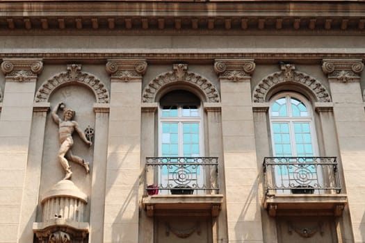 The facade of the neoclassical House, Palace of Merchant Andon Andonovic in the Obrenoviceva Street, the shopping street in the old town of Nis, elaborate carving, relief of the god mercury next to two decorated windows with small balconies, Nis, Serbia 2022