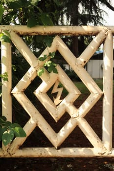Old, vintage, retro metal fence with electricity, high voltage, danger symbol at the electricity supplier, substation, distributor, power company, provider, electric utility, leaves from a tree, plant are growing in, Nis, Serbia 2022