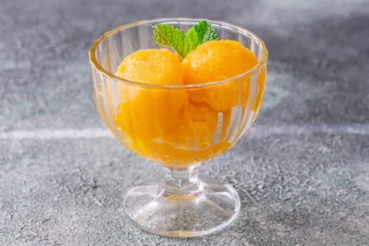 Mango sorbet scoop in the glass bowl