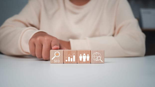 Business woman Point to the wooden block with the SEO icon, she use search engine to Searching for information, Using web Console for data, SEO. Point to the wooden block with the SEO icon.