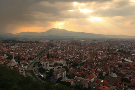 View from the Prizren Fortress onto the old town of Prizren before sunset, golden sunrays are breaking through the clouds, Prizren, Kosovo 2022