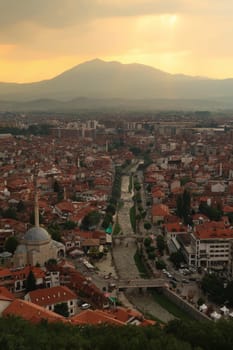 View from the Prizren Fortress onto the Bistrica River and the old town of Prizren before sunset, golden sunlight is breaking through a cloudy sky, Prizren, Kosovo 2022