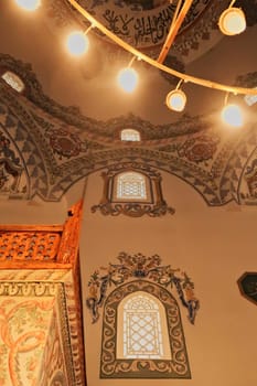 Elaborate ceiling and wall painting, fresco, decoration, pattern, ornament next to the golden chandelier inside the Sinan Pasha Mosque, an ottoman mosque in the old town of Prizren, Kosovo 2022