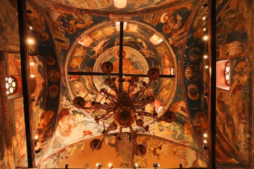 Chandelier hanging from a ceiling completely covered in colorful paintings, frescos inside the Church Complex of the Patriarchate of Pec Monastery, outside of Peja, Kosovo 2022