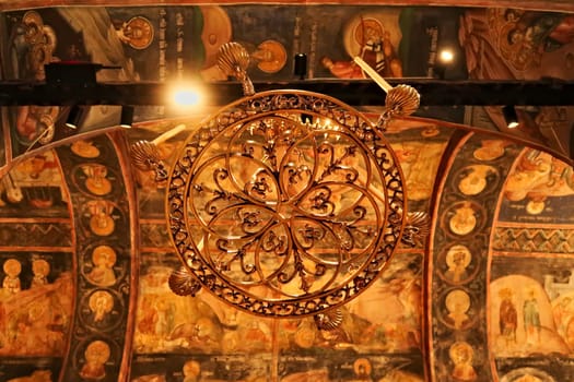 Chandelier inside the Church Complex of the Patriarchate of Pec Monastery, ceiling in the background is completely covered in colorful paintings, frescos, outside of Peja, Kosovo 2022