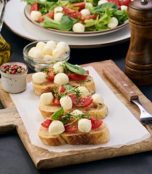 Round mozzarella, cherry tomatoes and microgreens on a piece of white bread, a healthy sandwich