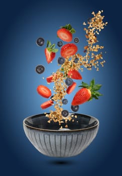 A ceramic bowl in which pieces of strawberries, blueberries, and muesli float in the air and fall, creating a feeling of dynamics and freshness on a gradient blue background