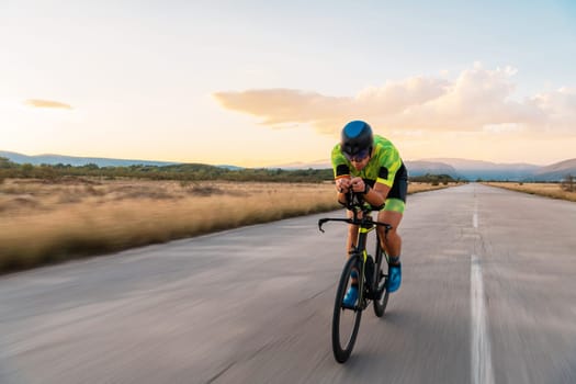Triathlete riding his bicycle during sunset, preparing for a marathon. The warm colors of the sky provide a beautiful backdrop for his determined and focused effort