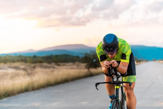 Triathlete riding his bicycle during sunset, preparing for a marathon. The warm colors of the sky provide a beautiful backdrop for his determined and focused effort