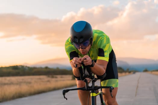 Triathlete riding his bicycle during sunset, preparing for a marathon. The warm colors of the sky provide a beautiful backdrop for his determined and focused effort