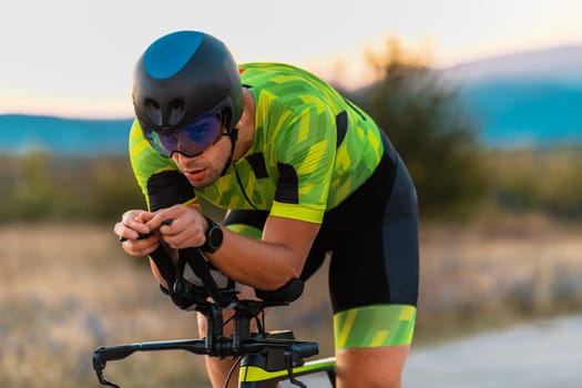 Close up photo of triathlete riding his bicycle during sunset, preparing for a marathon. The warm colors of the sky provide a beautiful backdrop for his determined and focused effort