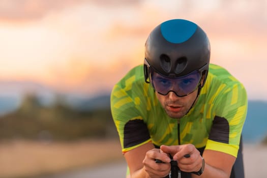 Close up photo of triathlete riding his bicycle during sunset, preparing for a marathon. The warm colors of the sky provide a beautiful backdrop for his determined and focused effort