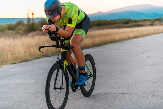 Triathlete riding his bicycle during sunset, preparing for a marathon. The warm colors of the sky provide a beautiful backdrop for his determined and focused effort