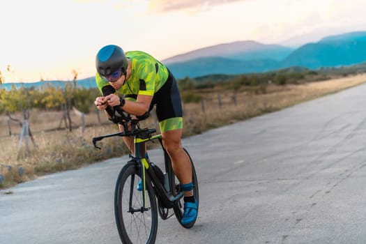 Triathlete riding his bicycle during sunset, preparing for a marathon. The warm colors of the sky provide a beautiful backdrop for his determined and focused effort